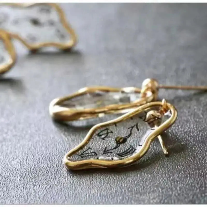 Unique clock earrings with irregular gold-tone frame and clear decorative clock-face charms.