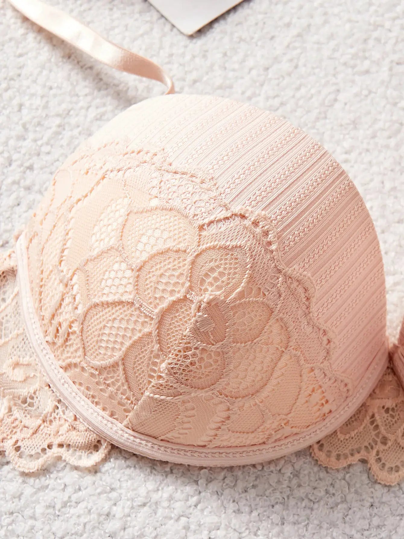 Peach-colored lace bra cup with floral pattern and striped band detail.