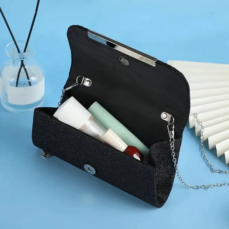 Simples Market black sequined party clutch with silver chain strap, open to reveal cosmetics