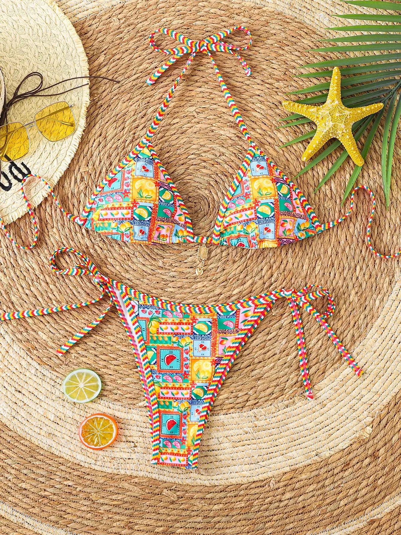 Triangle bikini set with floral print push-up top and Brazilian bottoms in bright multicolor pattern on straw mat