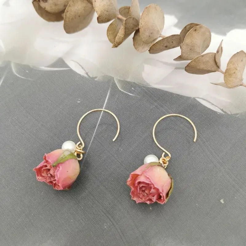 Pair of rose drop earrings with pink rose buds in epoxy resin, gold hooks and pearl beads, by Simples Market