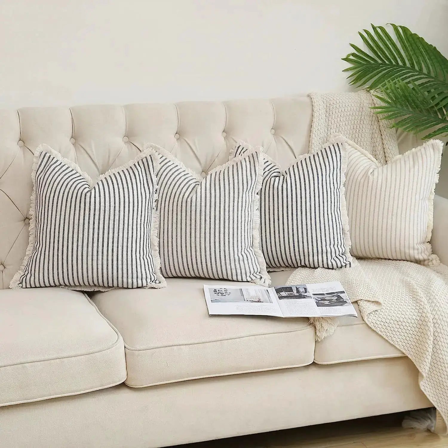 Set of four wool striped square cushion covers with fringed edges on a cream tufted sofa