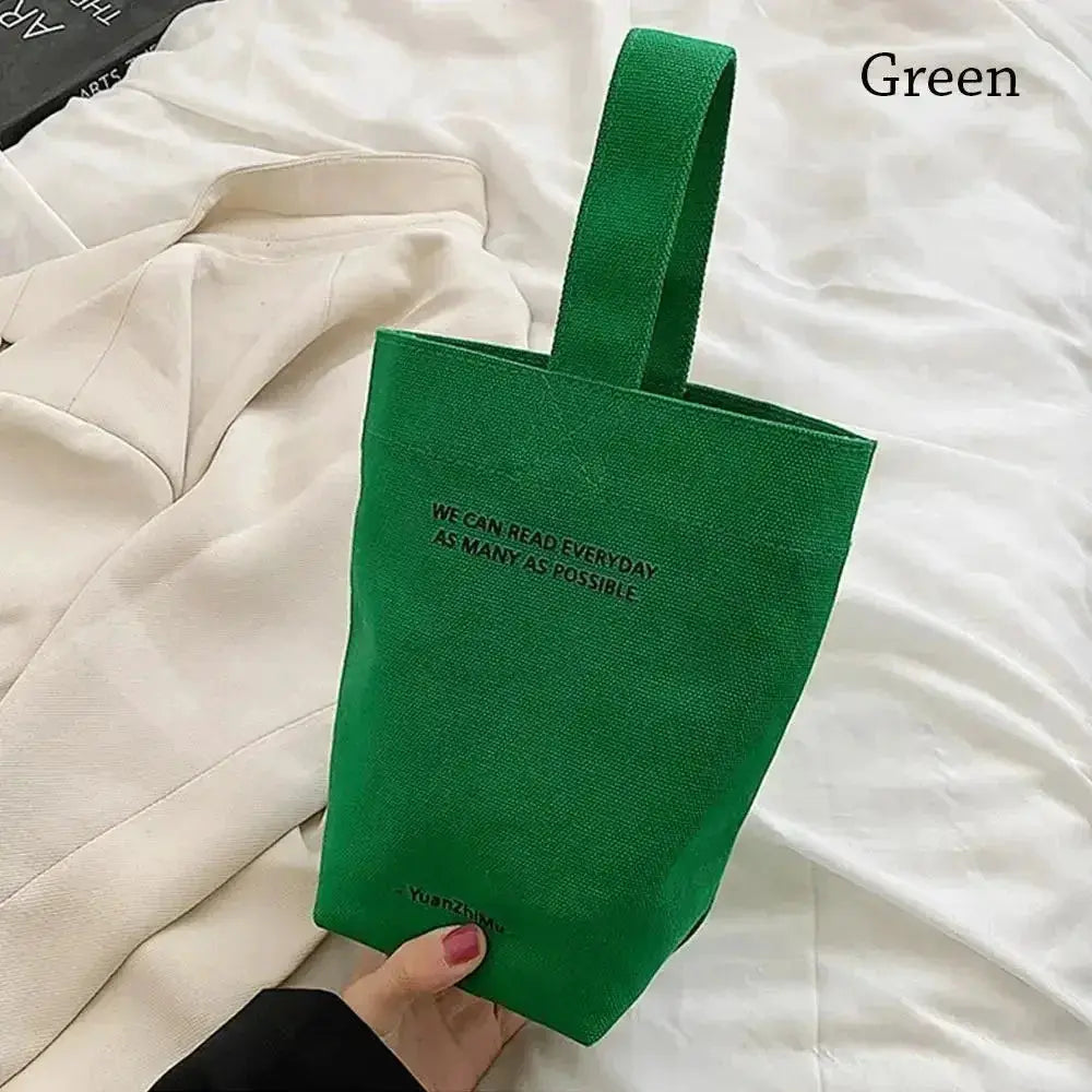 Green canvas tote bag with top handle, large-capacity design, and black slogan print.
