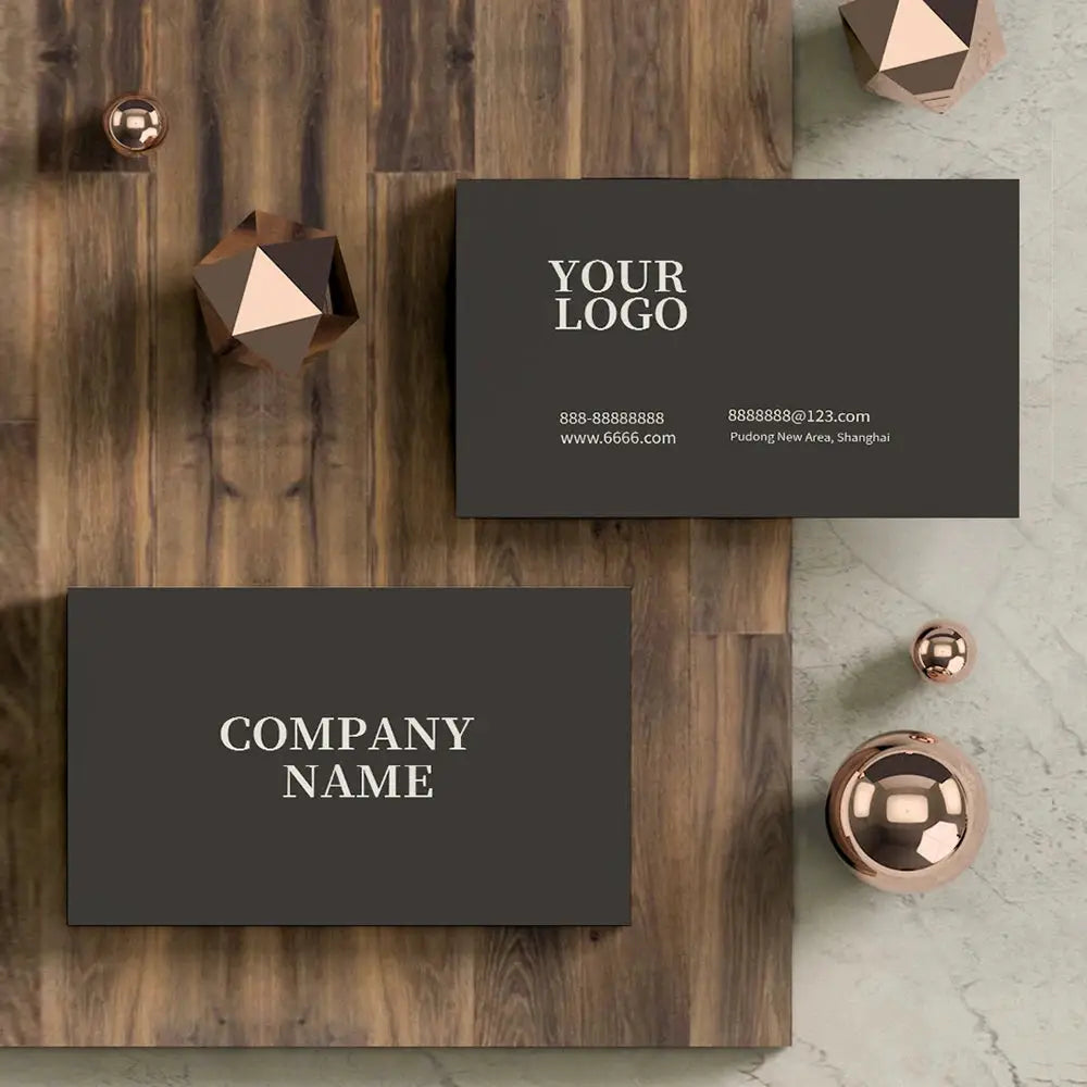 Custom business cards by Simples Market; two dark gray cards with white logo text on a wood desk.