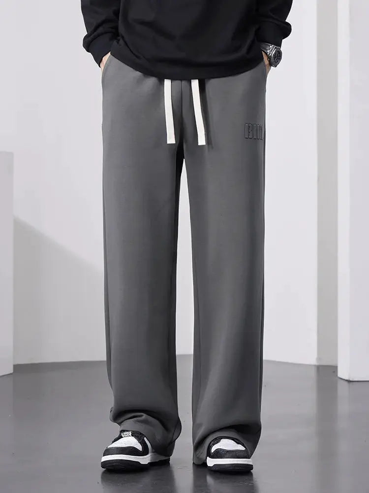 Men's grey wide-leg cotton track pants with drawstring for a baggy casual look.