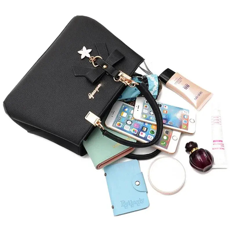 Black women's shoulder bag with bowknot charm and gold hardware, with phone and wallet spilling from the bag
