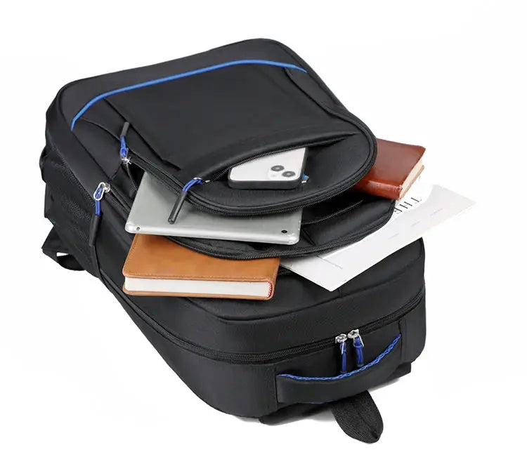 Simples Market black backpack with blue zippers, large-capacity travel/office/school bag shown with six items: phone, tablet, laptop, notebook, book, papers.