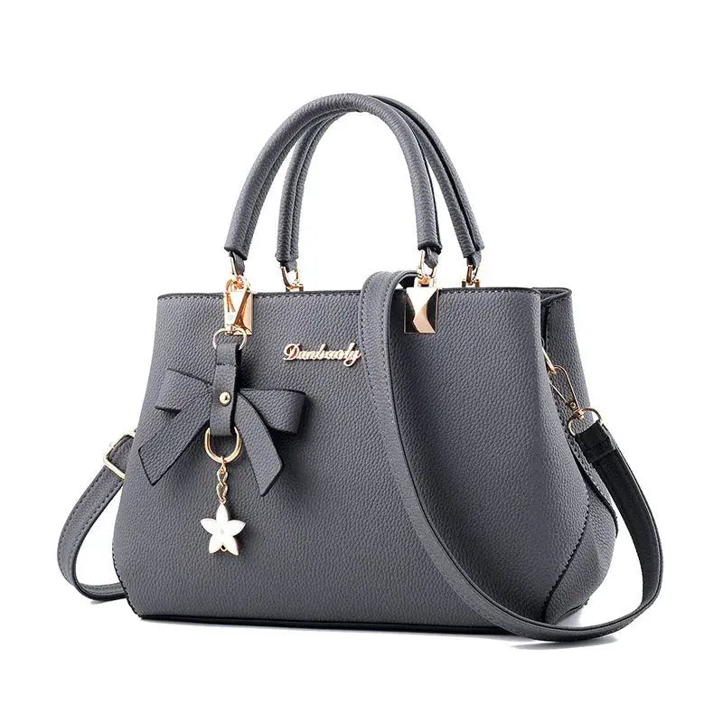 Bow handbag gray faux leather by Simples Market with double top handles, removable crossbody strap, gold-tone hardware.