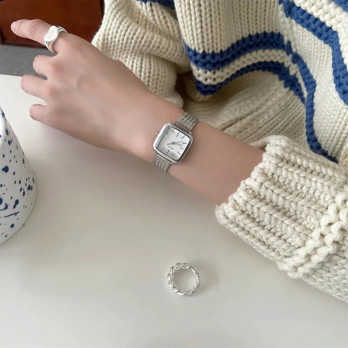 Simples Market women's square quartz watch with small dial and silver stainless steel bracelet.