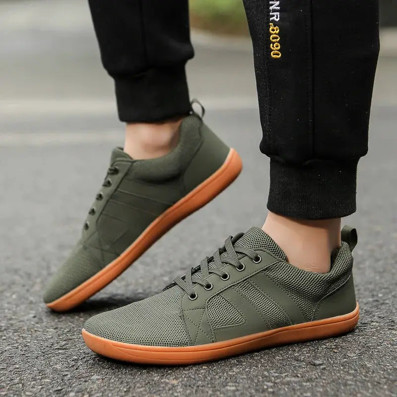 Wide-toed olive green casual athletic shoes with orange sole and mesh upper.