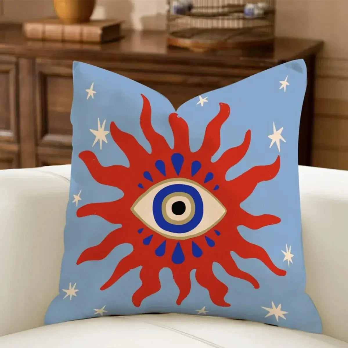 Pillow cover by Simples Market; sky-blue Boho decor with bold red sunburst around a central eye motif.