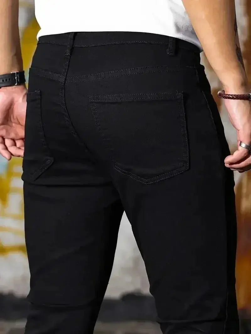 Men's slim-fit black denim jeans with back pockets, casual street style.