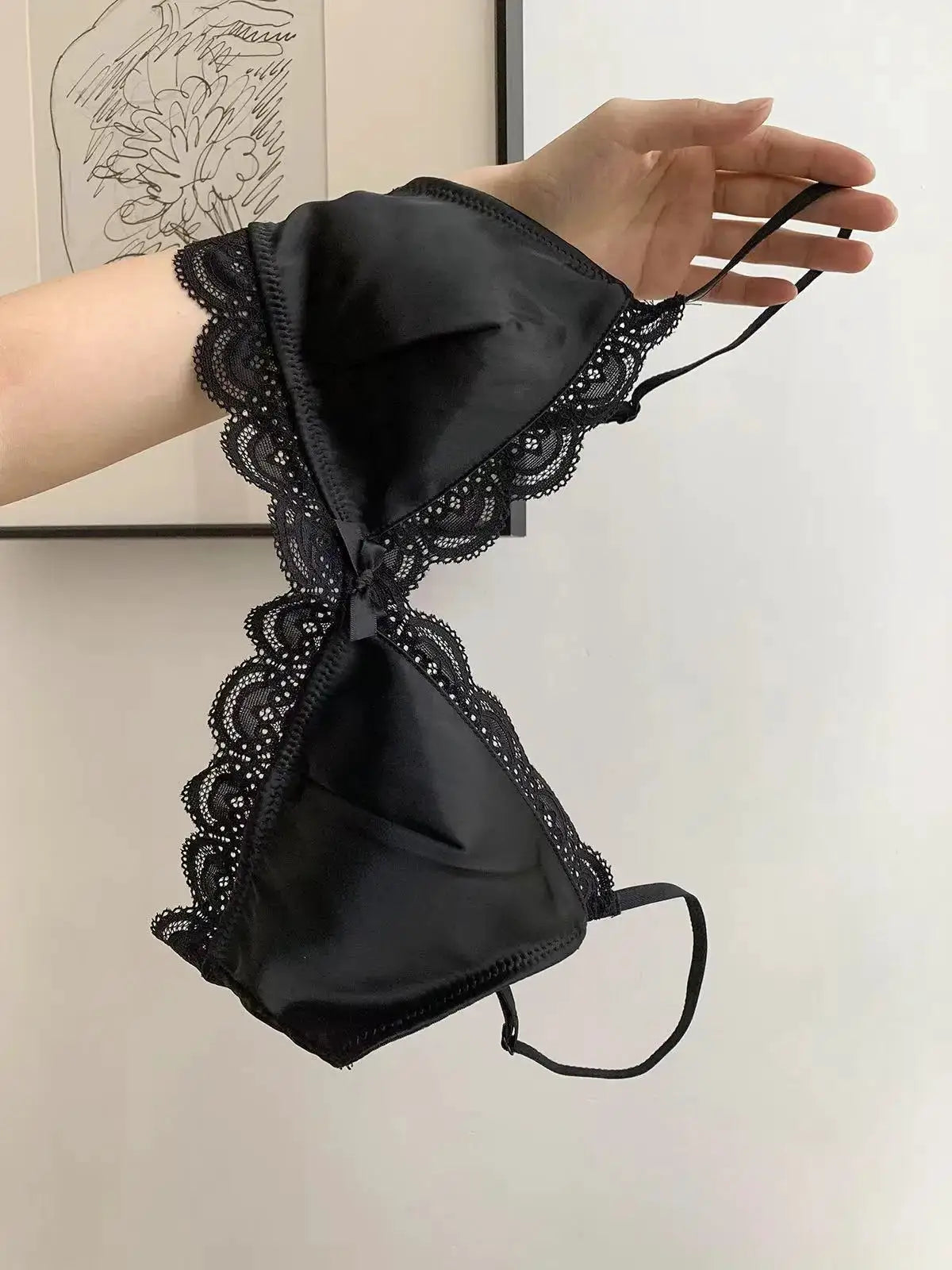 Black satin triangle-cup bra with scalloped lace trim and bow centerpiece
