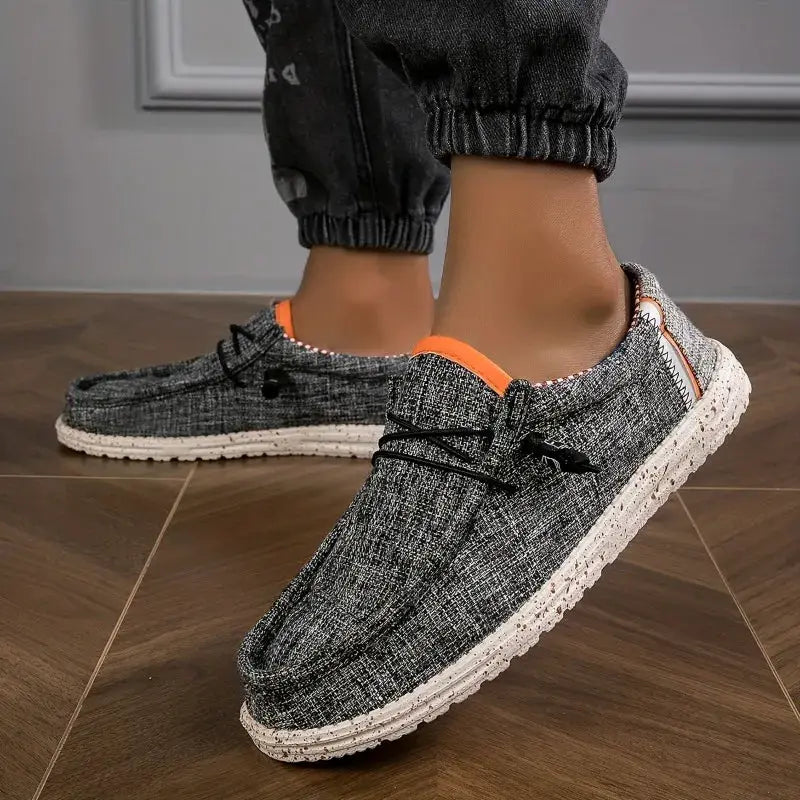 2 gray men's canvas loafers with orange trim and speckled white sole