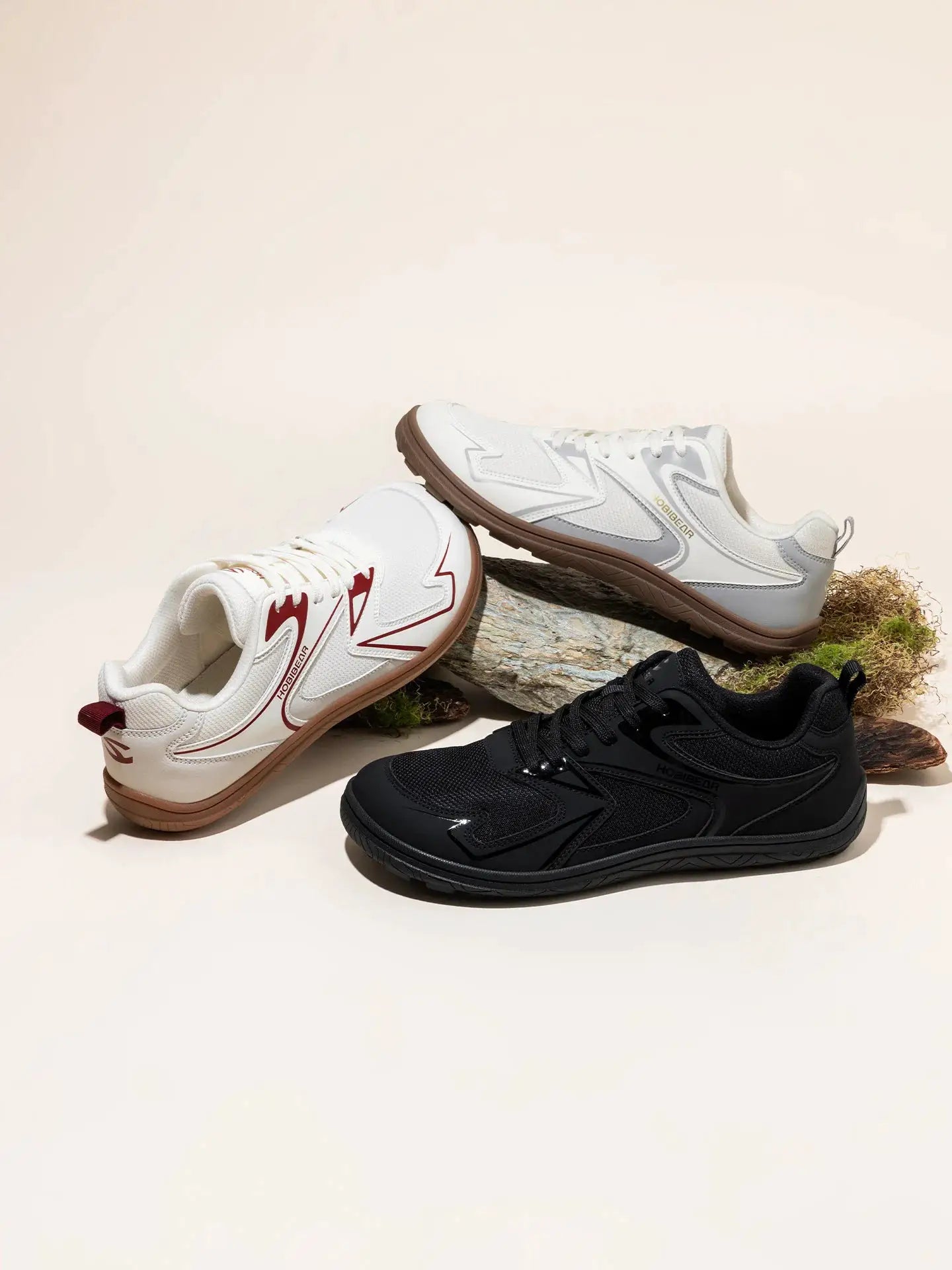 3 pairs of HOBIBEAR barefoot minimalist shoes in white, gray, and black on a rock display