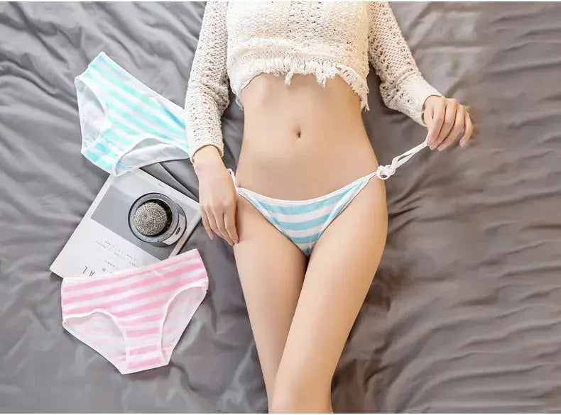 Cotton panties set: three pastel striped briefs in blue/white and pink/white, worn by a model on a bed.