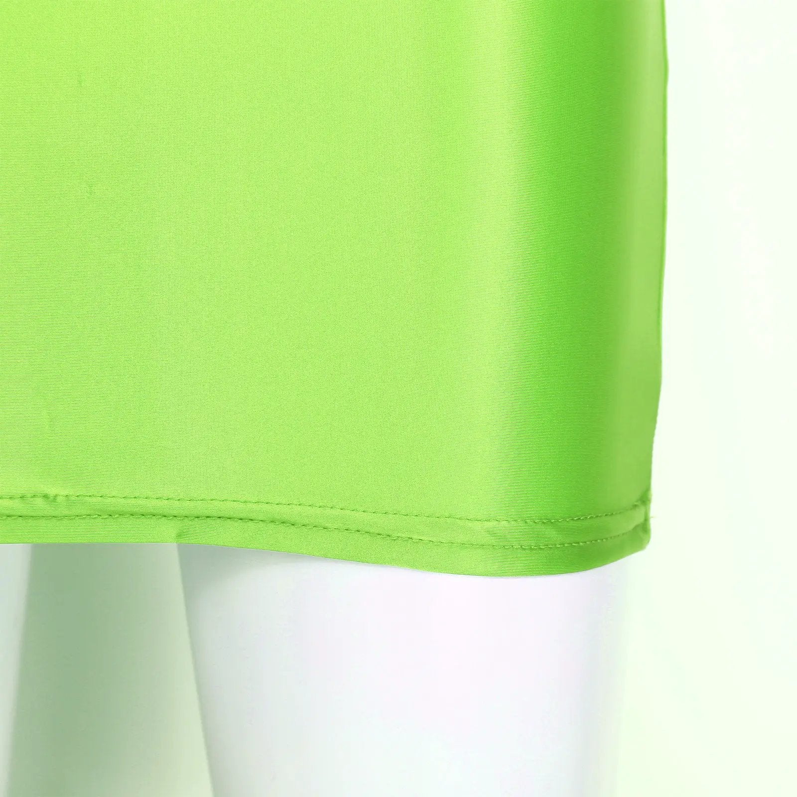 Glossy lime green patent leather mini skirt close-up hem detail