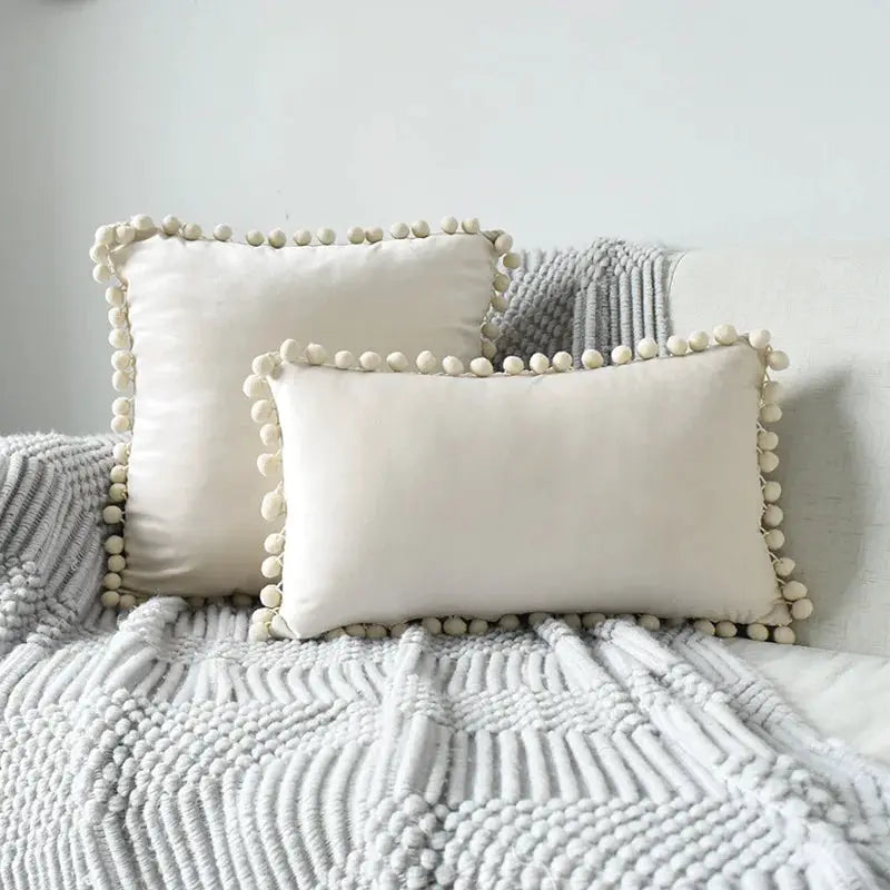 Velvet cushion covers with pom-pom fringe, set of 2 cream Boho pillows on a gray knit blanket.