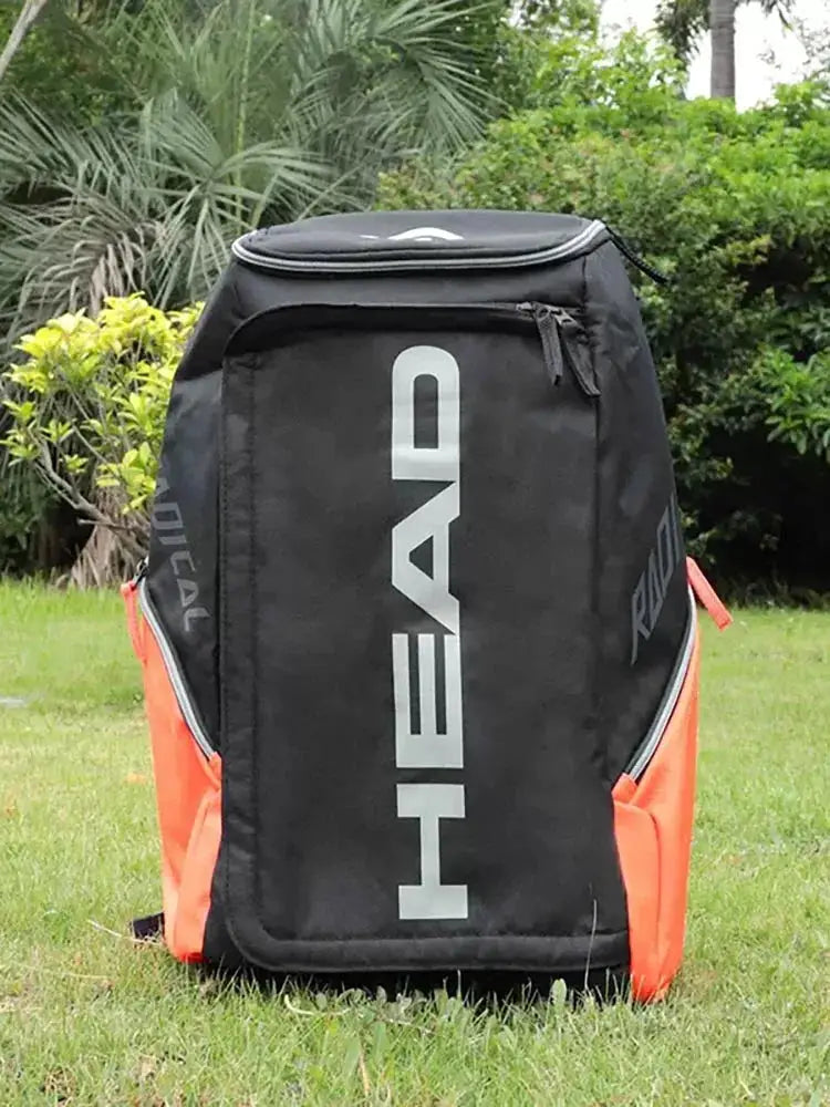 HEAD Original Radical Tennis Backpack, black with orange side pockets and large white HEAD logo.