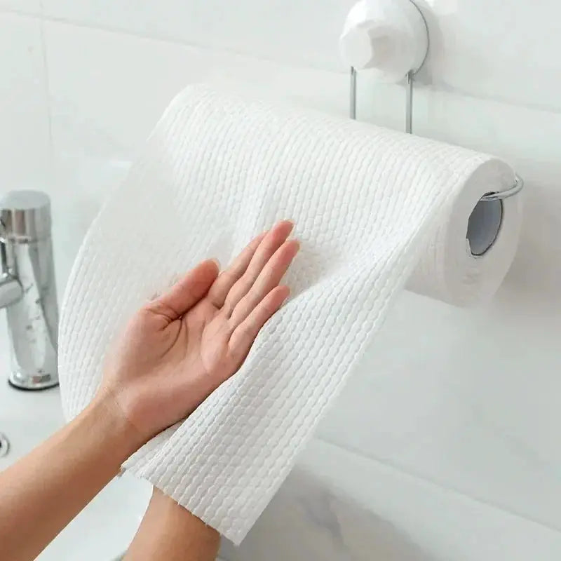 Simples Market white non-woven disposable kitchen cleaning cloths on roll, pulled from wall-mounted holder.