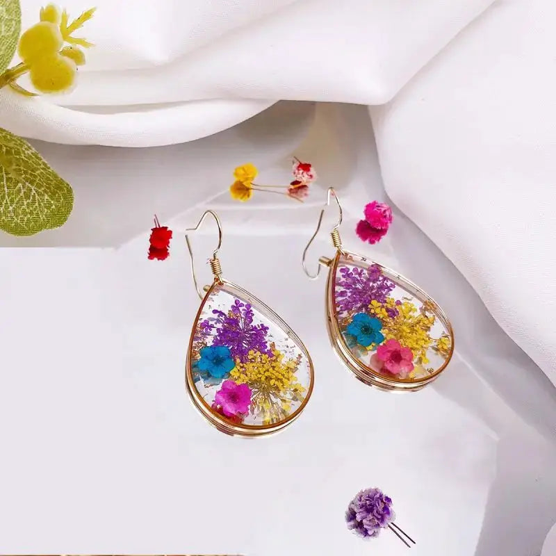 Pair of teardrop epoxy resin earrings containing colorful pressed flowers in a gold-tone frame