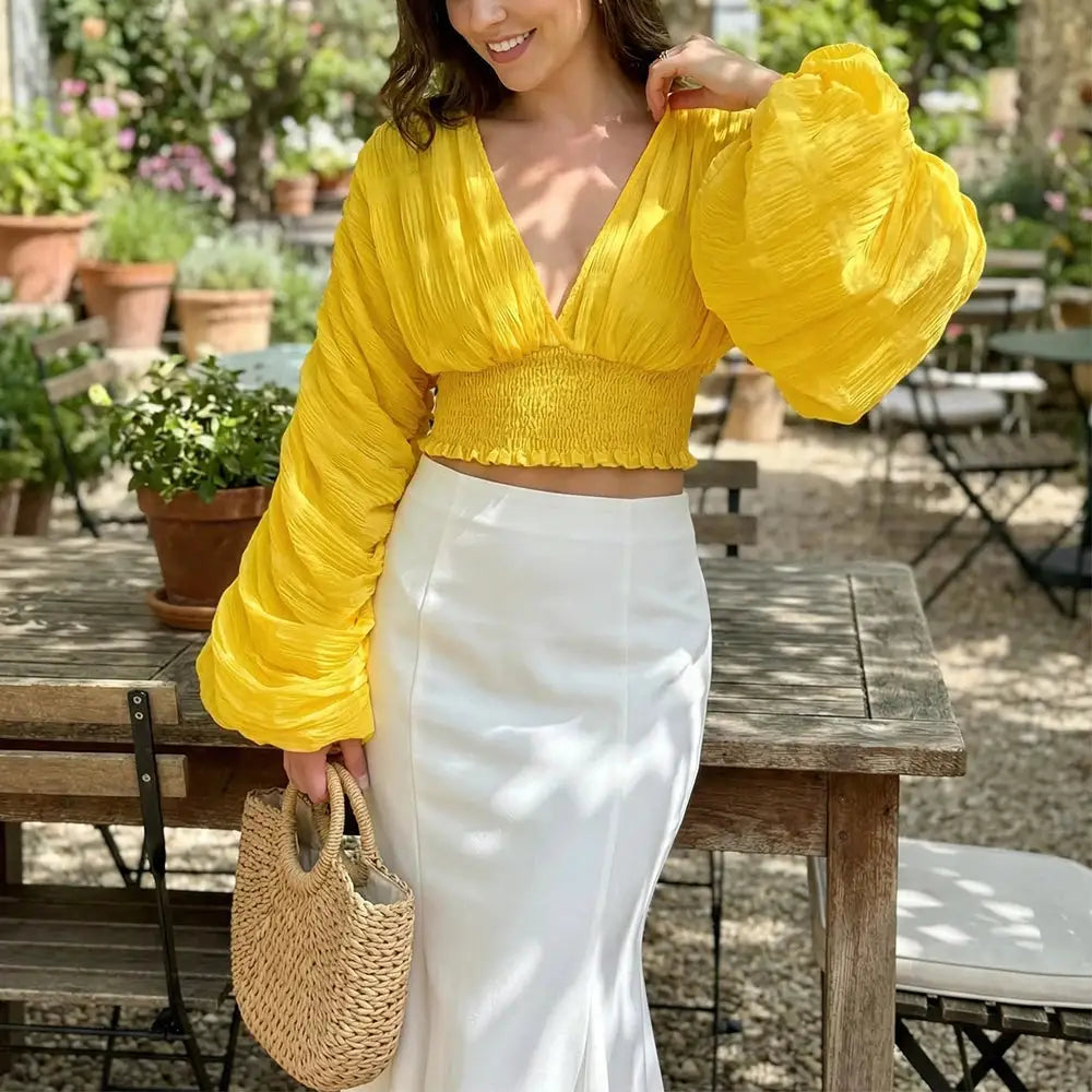 Women's yellow draped chiffon blouse with V-neck and puff long sleeves.