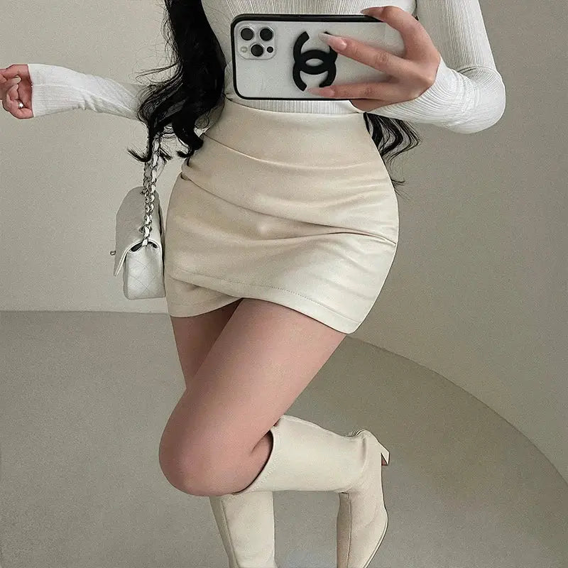 WOMENGAGA PU leather mini wrap skirt, high-waisted beige with wrinkle-wrapped silhouette, Chanel phone case visible