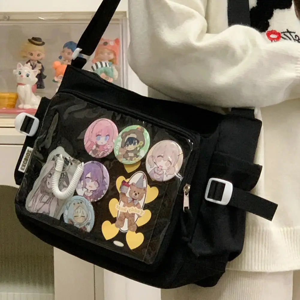Black Ita bag with clear front window featuring cartoon pin charms; adjustable strap
