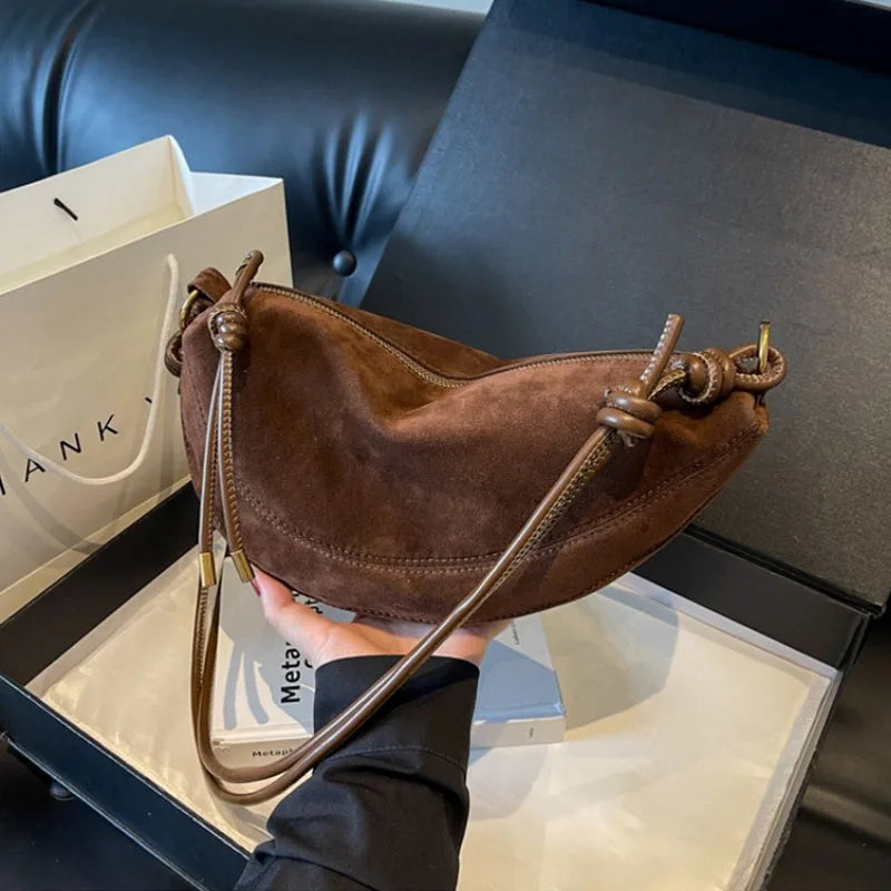Brown suede shoulder bag with knotted drawstring straps, crossbody style.
