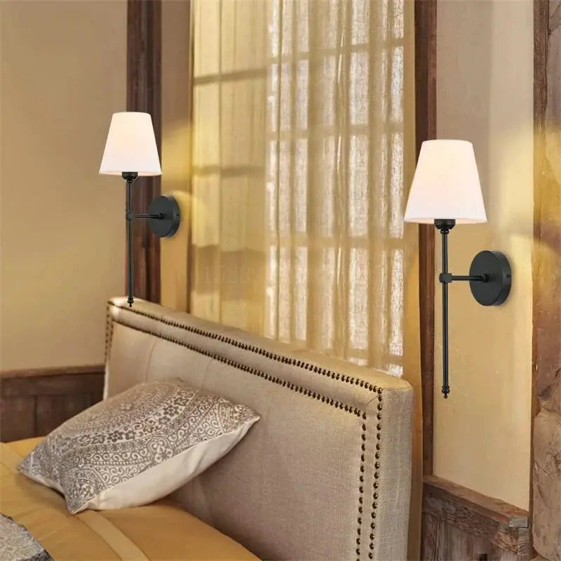Modern American wall lamp pair hardwired with cloth shades, black metal sconces mounted on bedroom walls beside the headboard.