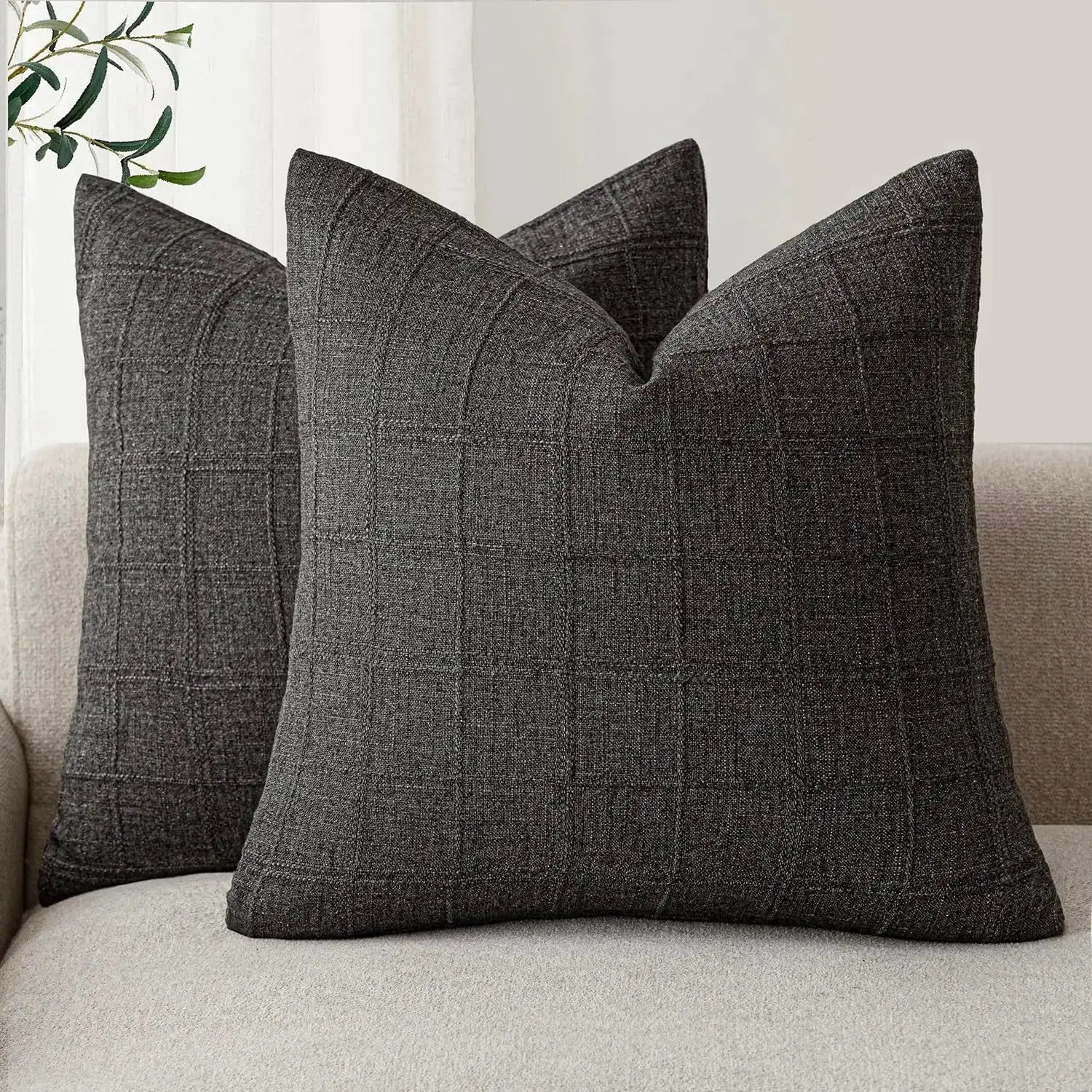 Dark gray plaid square cushion covers on a beige sofa