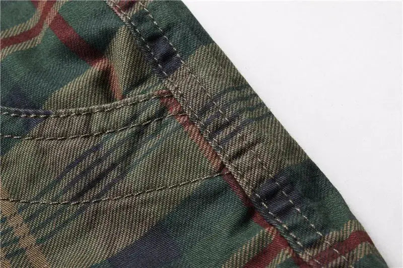Men's plaid shorts fabric close-up in green and brown tones with visible stitching