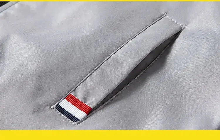 Men's lightweight gray windbreaker jacket with red, white and blue striped pocket tab