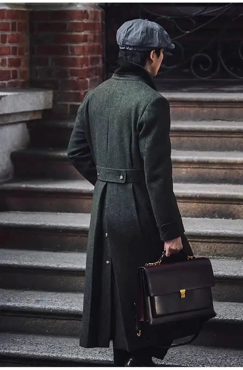Men's green wool-blend overcoat, long belted and double-breasted, shown with a brown leather briefcase