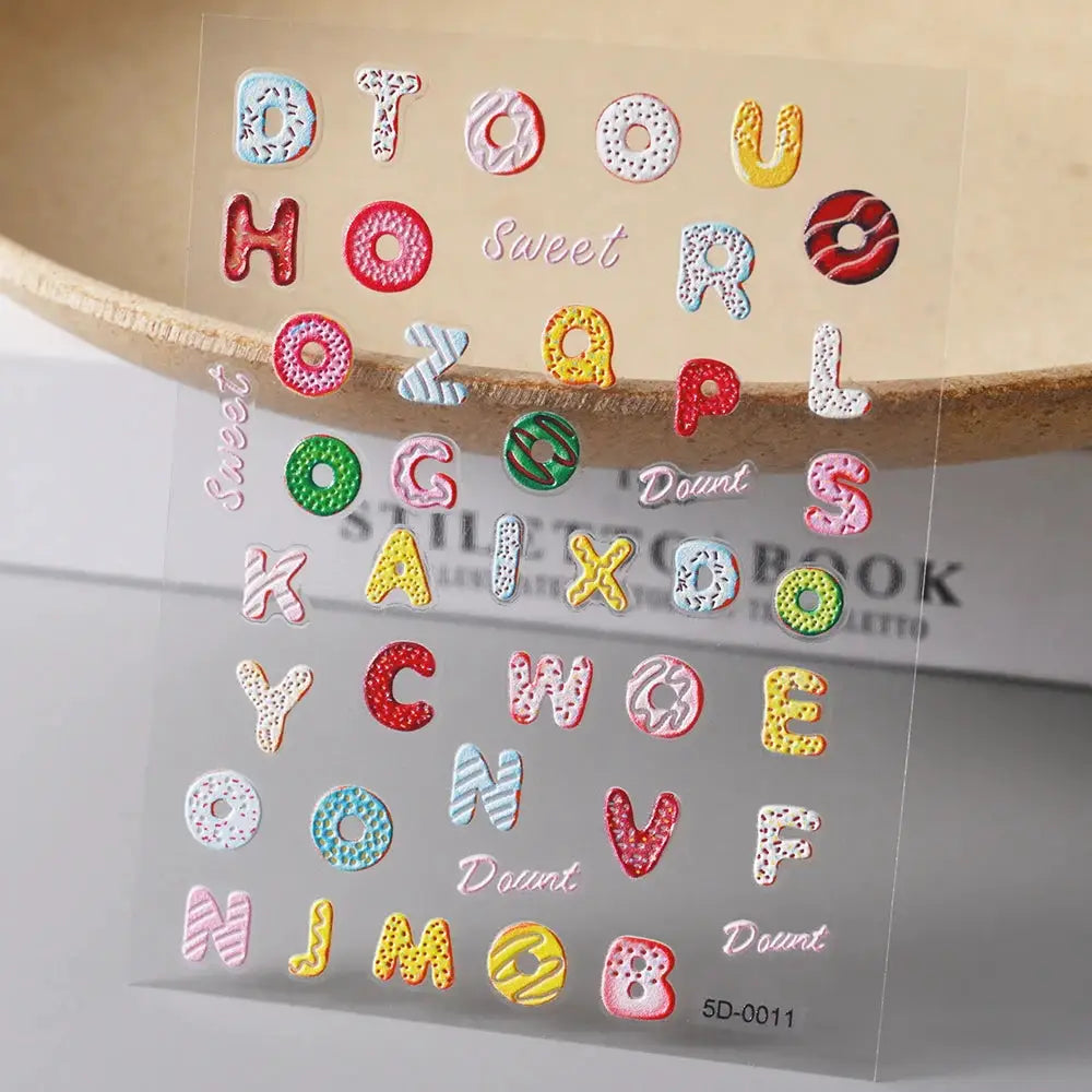 Nail art sticker sheet with colorful embossed alphabet letters and donut/macaron shapes for manicure