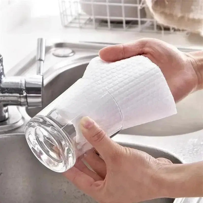 Simples Market kitchen disposable non-woven cleaning cloth, white, being wiped on a glass.