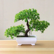 Artificial bonsai tree in a white rectangular pot with vibrant green leaves.