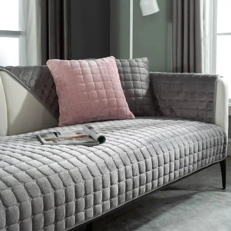 Velvet sofa cover in grey plaid plush, non-slip thickened warm flannel, placed on living room sofa with a pink cushion.