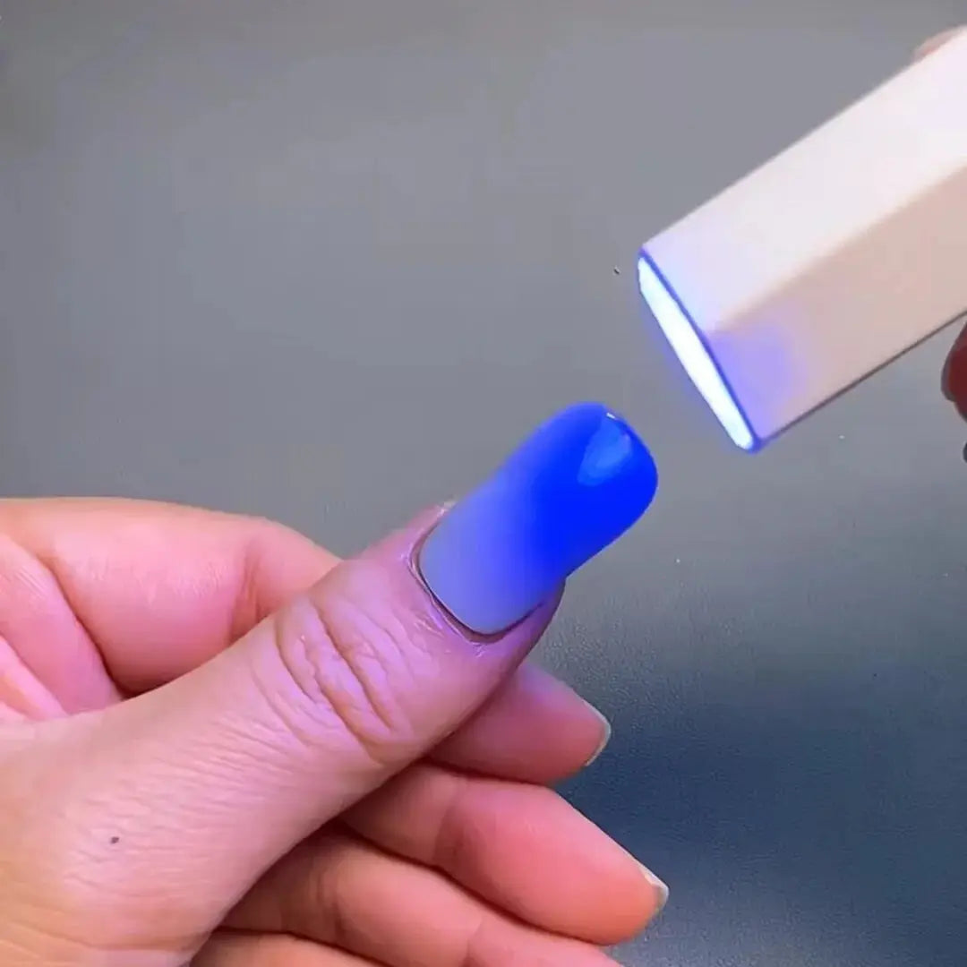 Semi-cured gel nail wraps in blue on a fingernail under a small LED lamp