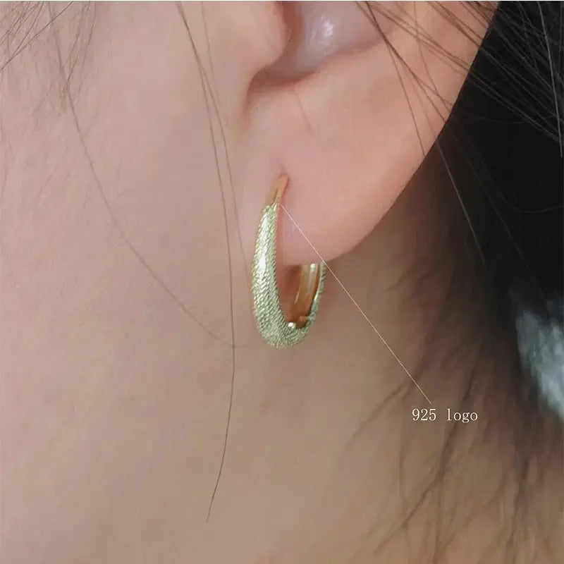 Hoop earring with frosted textured finish worn in the ear