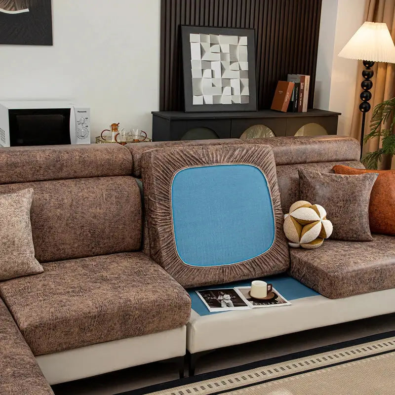 Stretch sofa cushion cover by Simples Market with blue center panel and brown fringe on a brown sectional sofa.