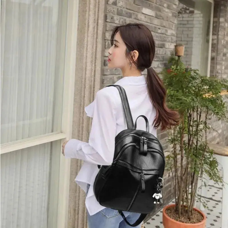 Black women's backpack with multiple zip pockets and bear charm.