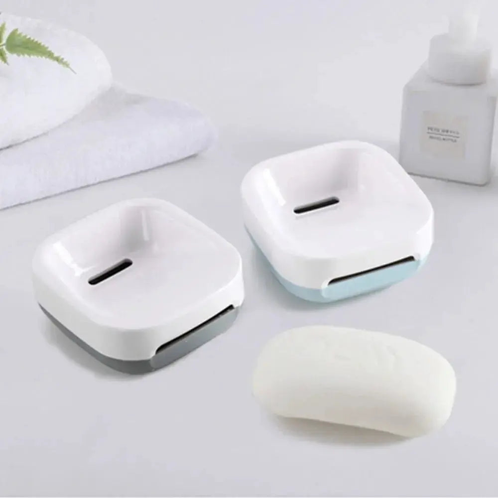 Two white electric toothbrush holders with gray and light-blue bases on a bathroom countertop beside towels and a lotion bottle.