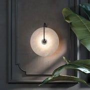 Nordic wall sconce by Simples Market; marble moon disk LED light, black cord, warm bedside glow.