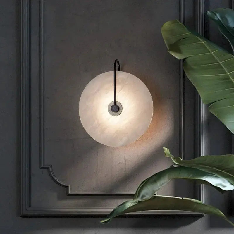 Nordic wall sconce by Simples Market; marble moon disk LED light, black cord, warm bedside glow.
