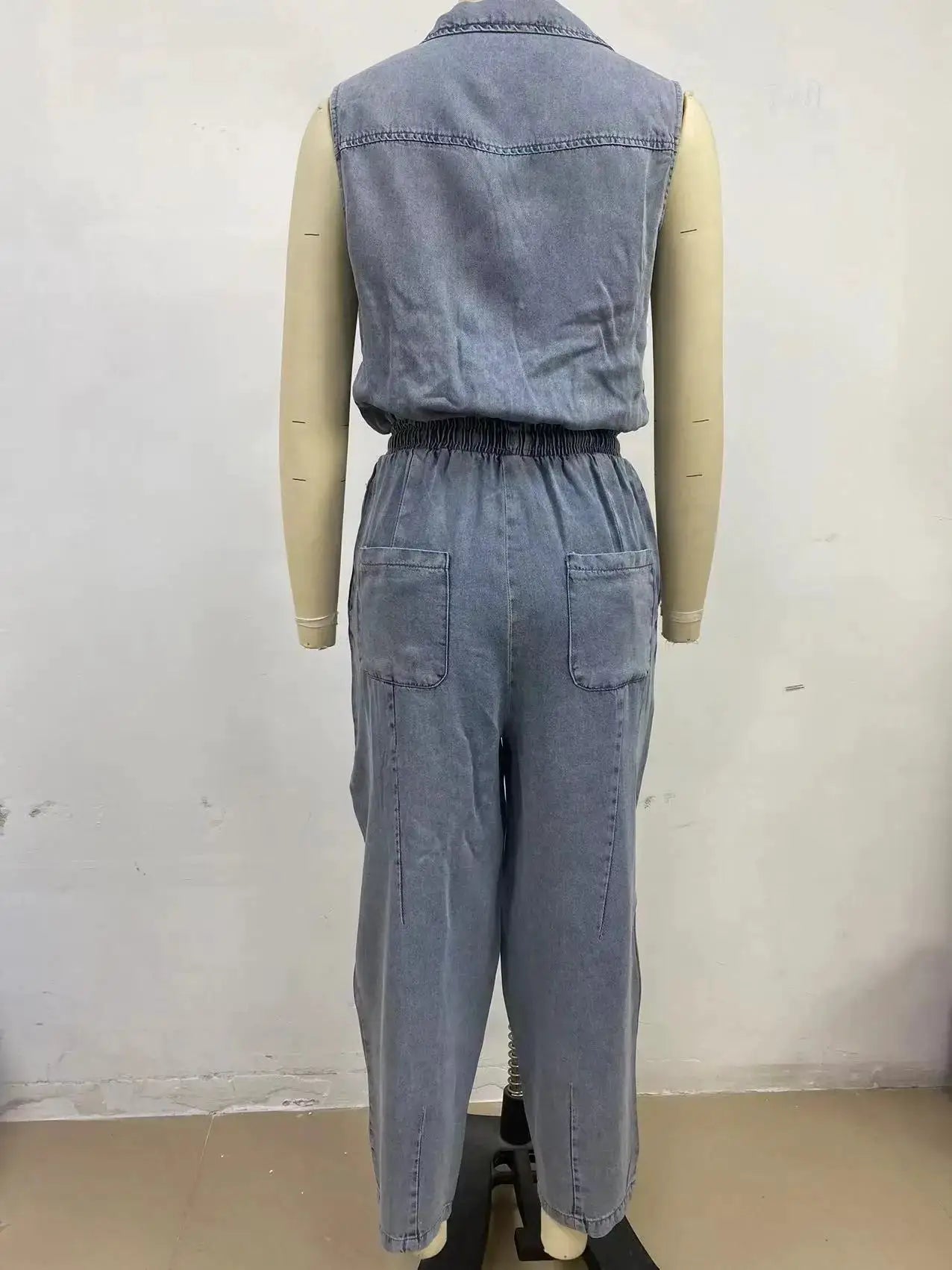 Denim sleeveless jumpsuit back view with elastic waist and patch pockets