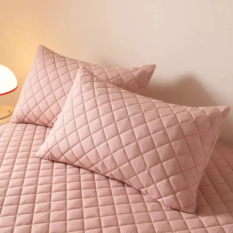 Two pink quilted cotton pillowcases with a diamond stitch on a bed