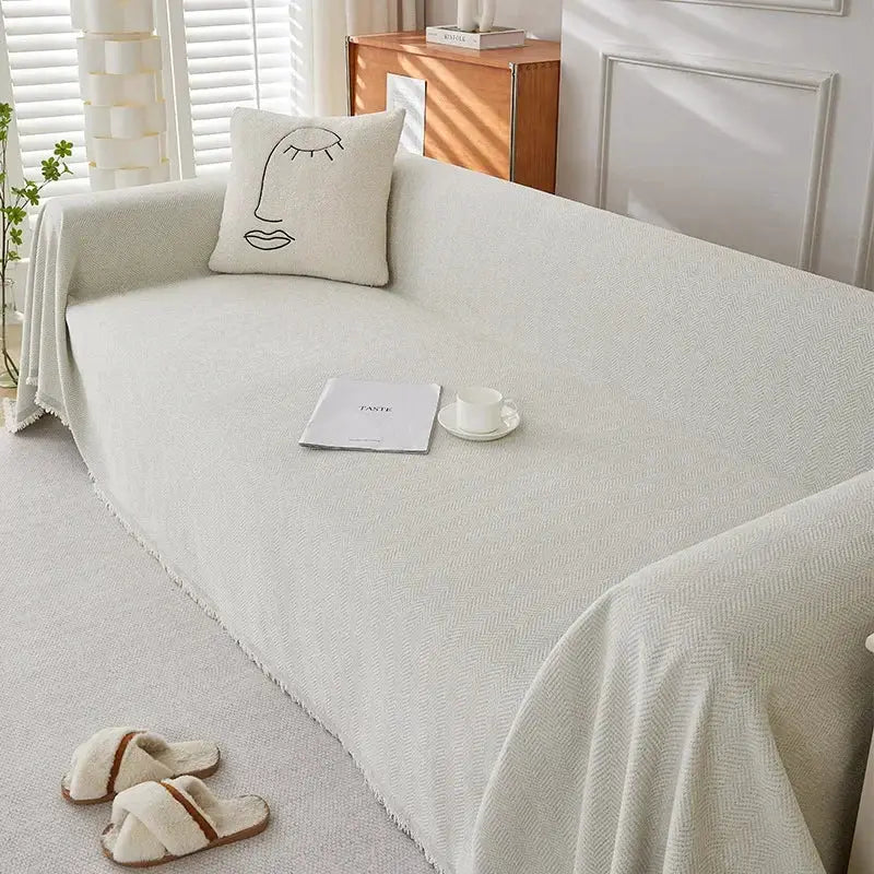 Beige chenille couch cover with fringe and herringbone texture, heavyweight throw for couch and bed decor.