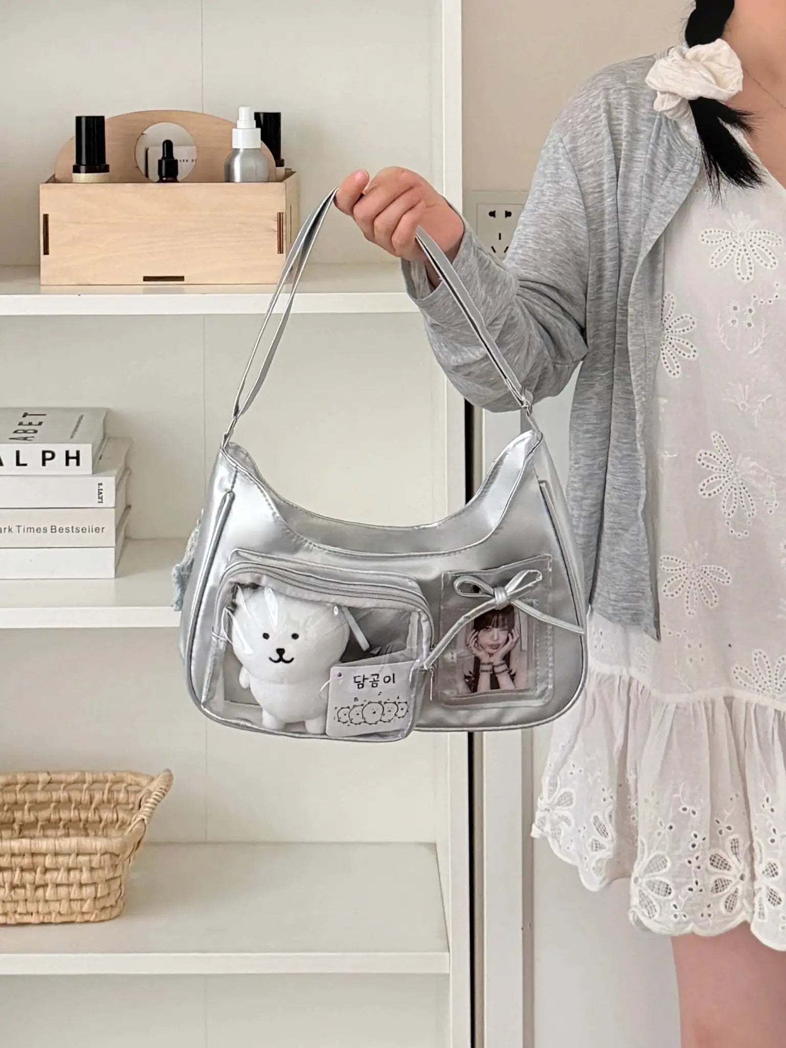 Silver transparent ita bag with shoulder strap front zip pockets and teddy bear keychain