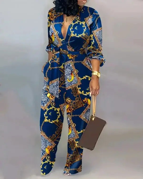 Blue letter-print long-sleeve jumpsuit with gold chain motif and cinched waist.